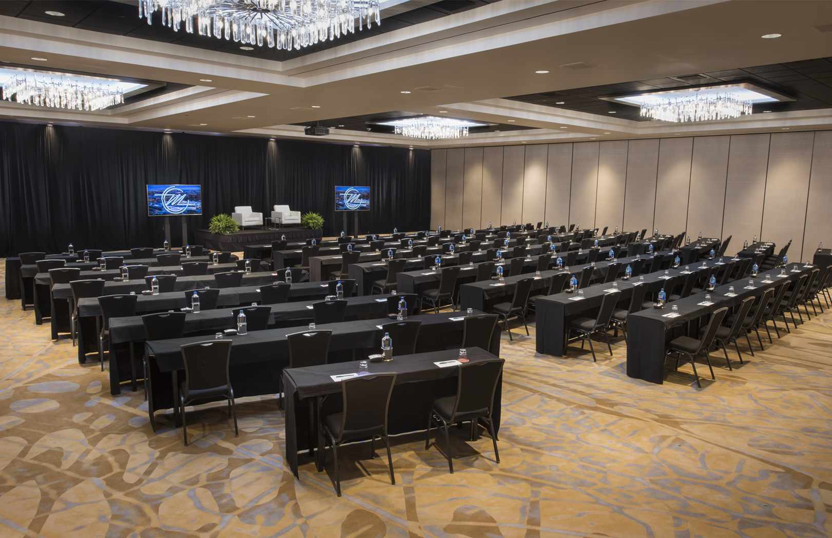 Convention center meeting setup with rows of black tables and chairs