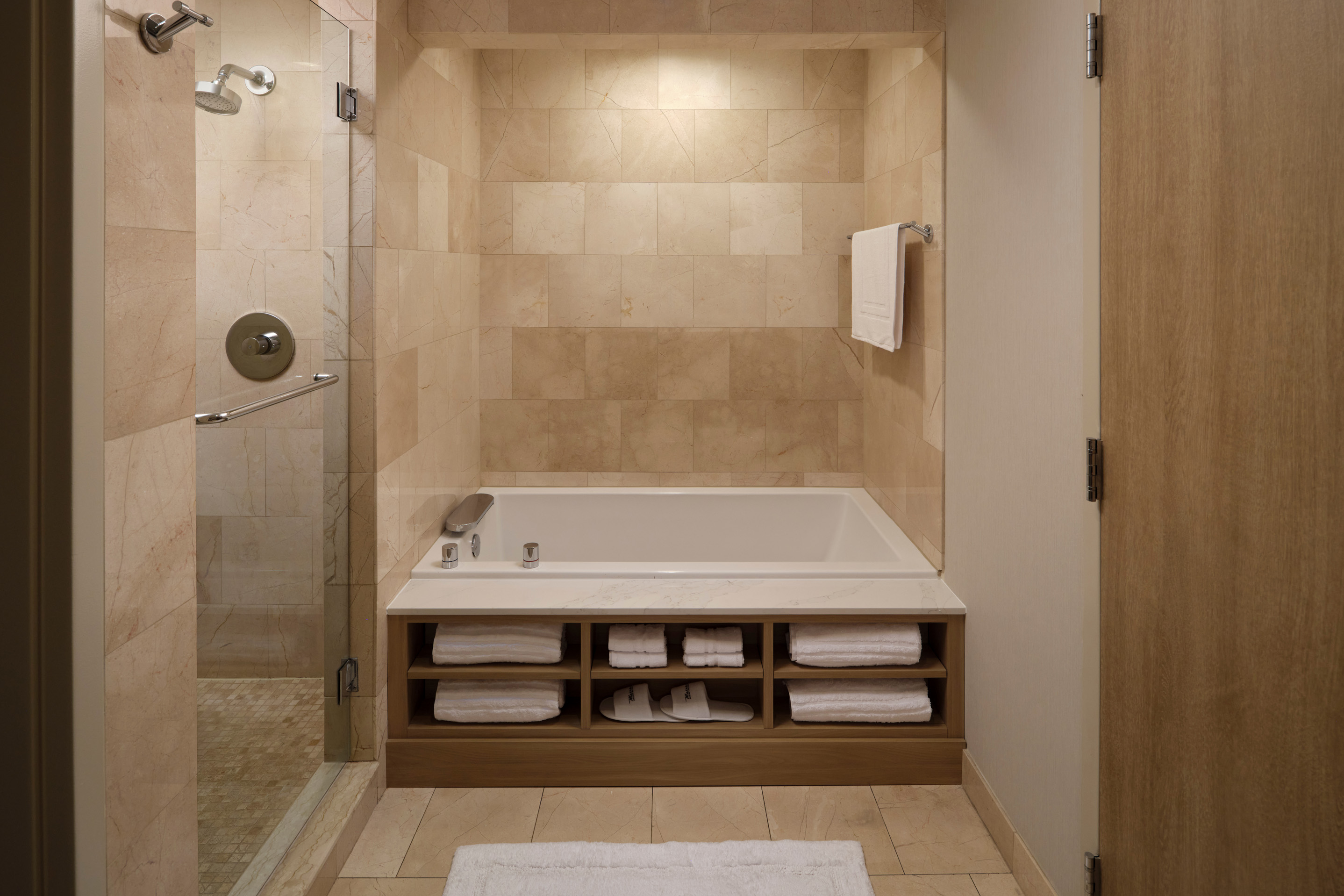 Walk-in hotel shower with marble tile, rainfall shower, and built-in bench