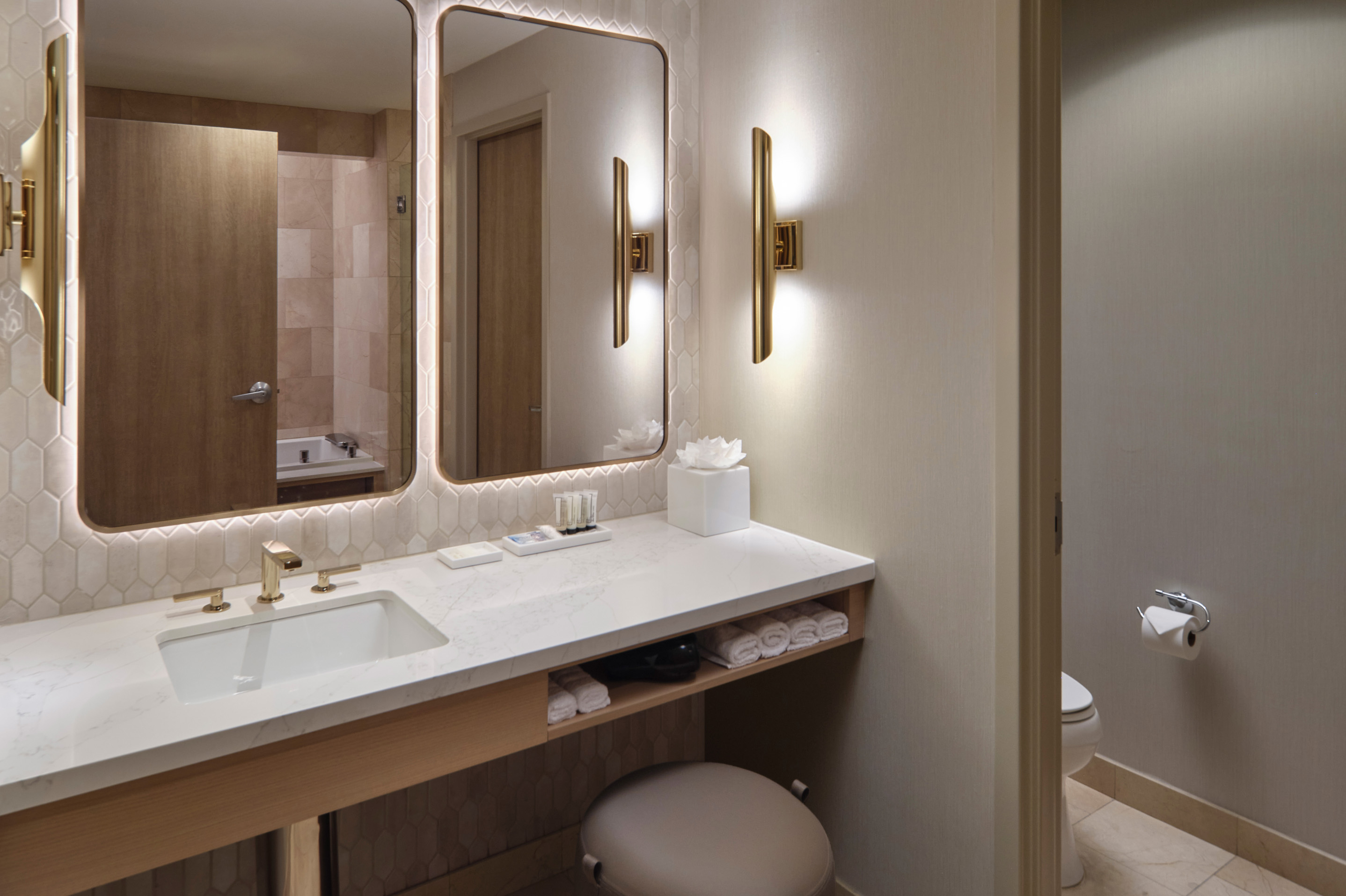 Luxury hotel bathroom with double vanity, illuminated mirrors, and modern wood finishes