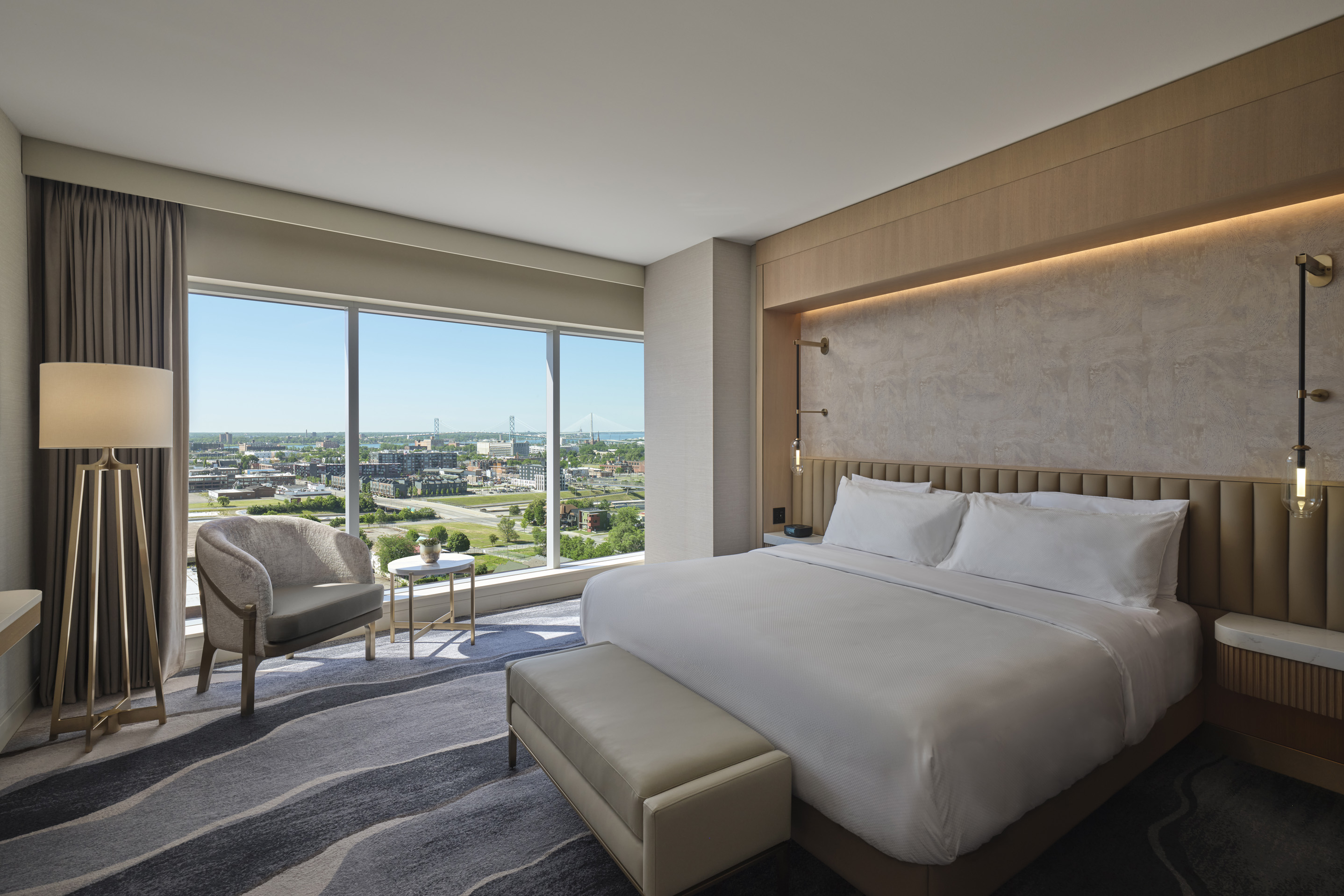 Luxury king hotel room with floor-to-ceiling windows and panoramic Detroit skyline views