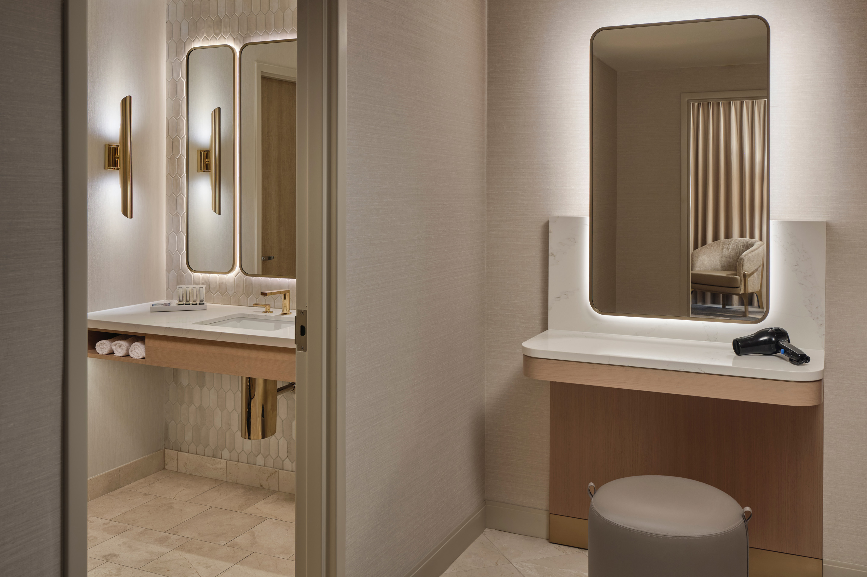Modern hotel suite vanity and dressing area with illuminated mirror and wood finishes