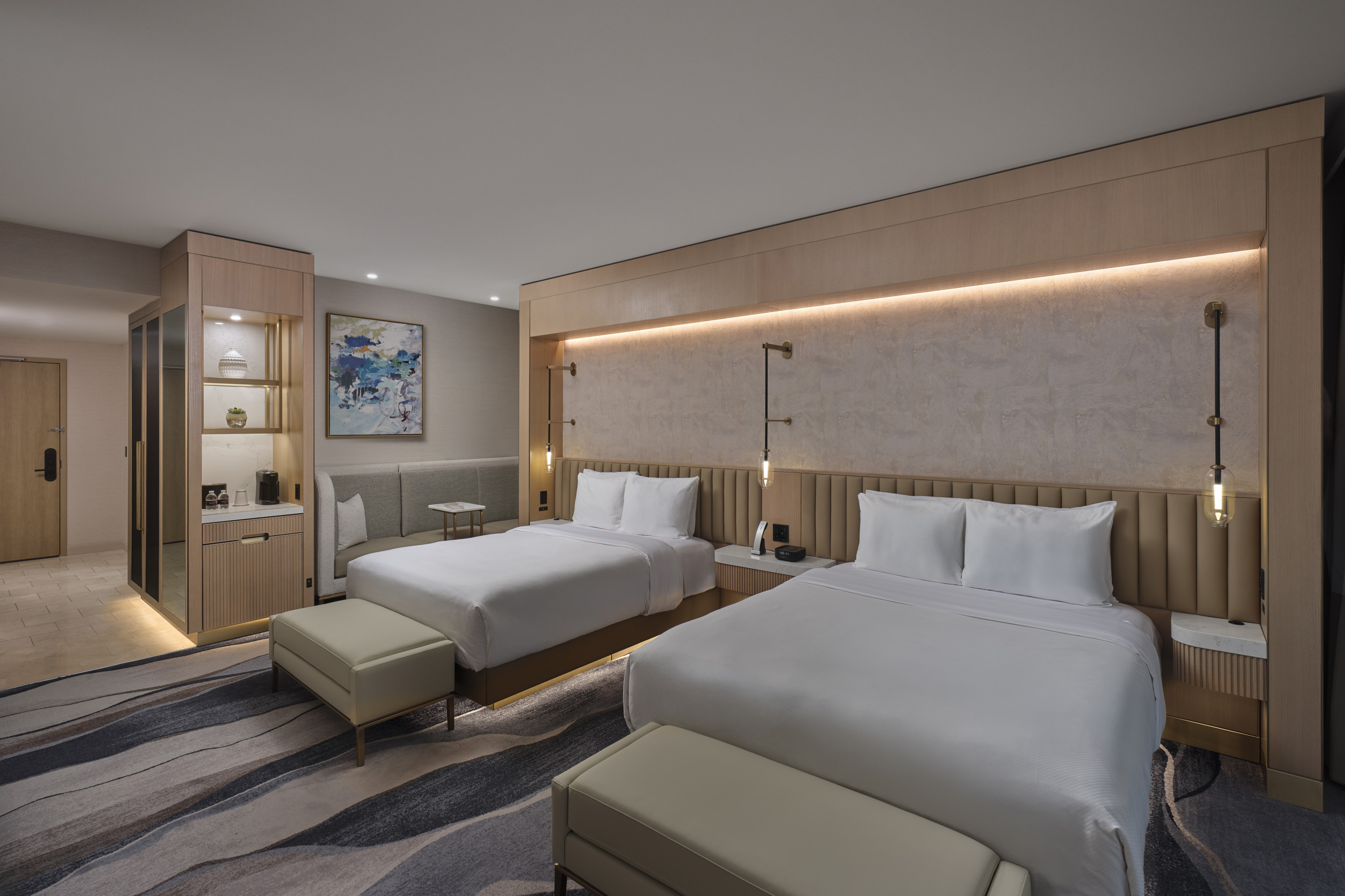 Spacious hotel guest room with king bed, lounge seating, and contemporary interior design