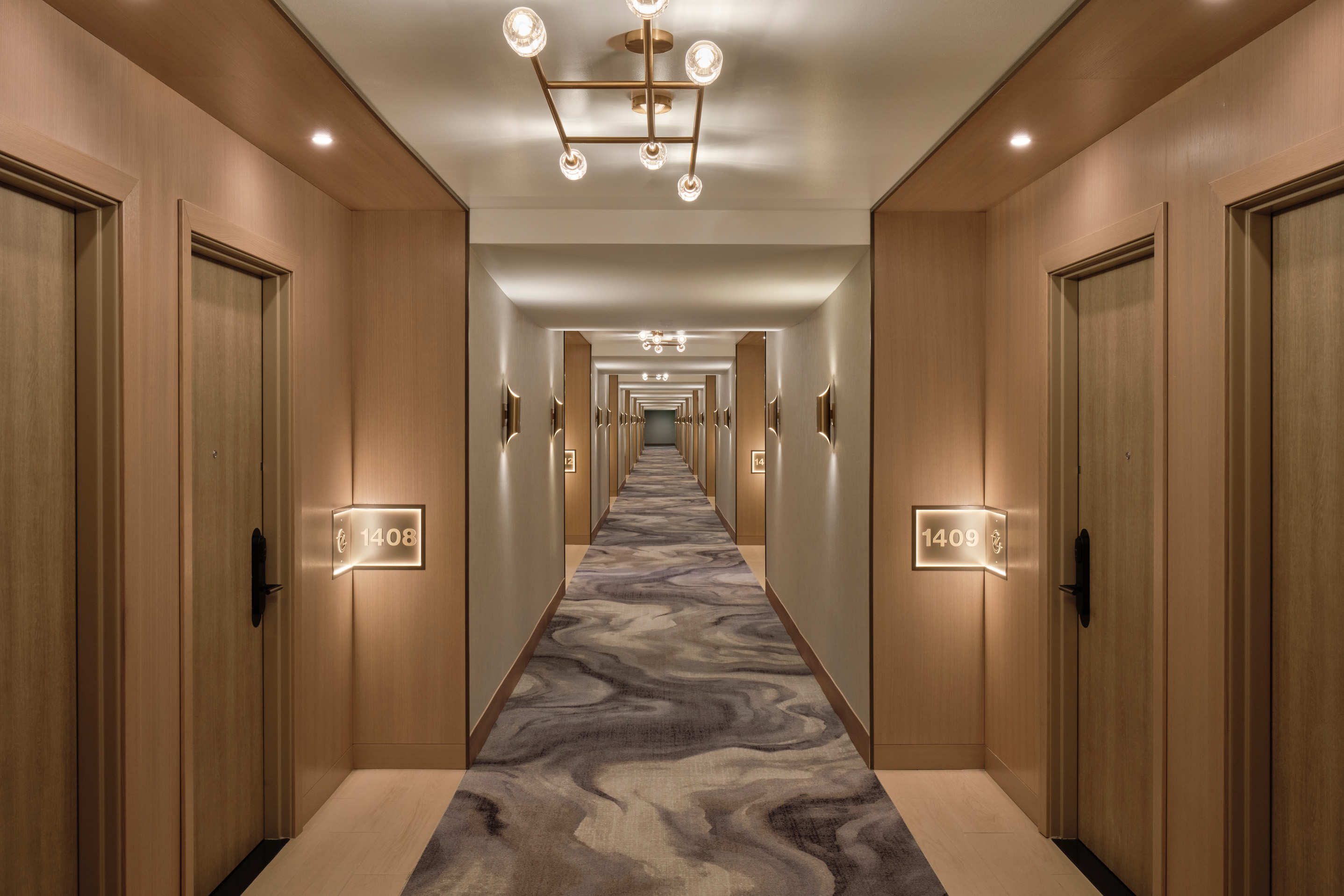 Elegant hotel corridor with warm wood paneling, modern lighting, and patterned carpet